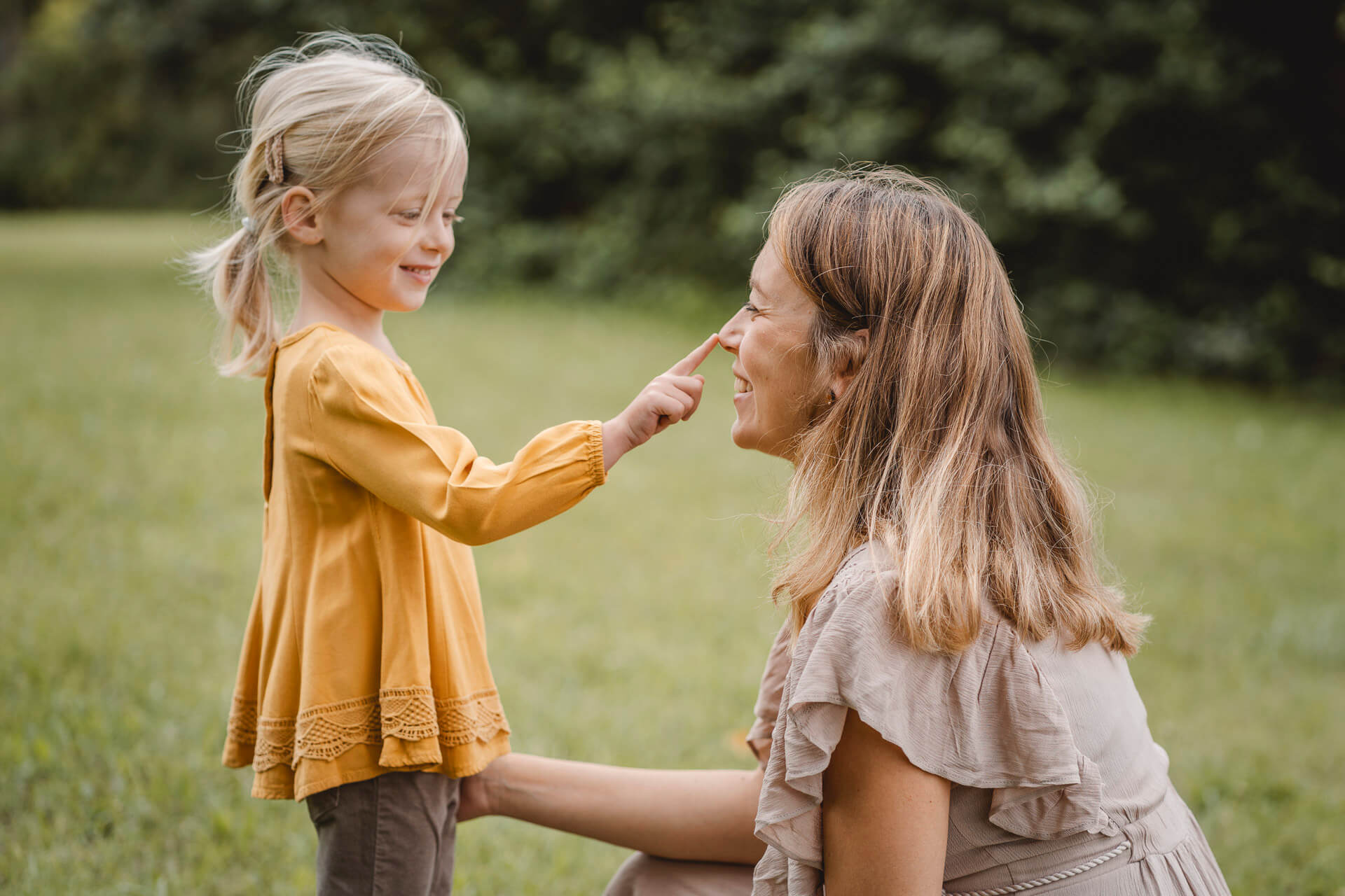 Kleines Mädchen läuft lachend an seiner Mama vorbei, fotografiert bei einem Familien Fotoshooting in München