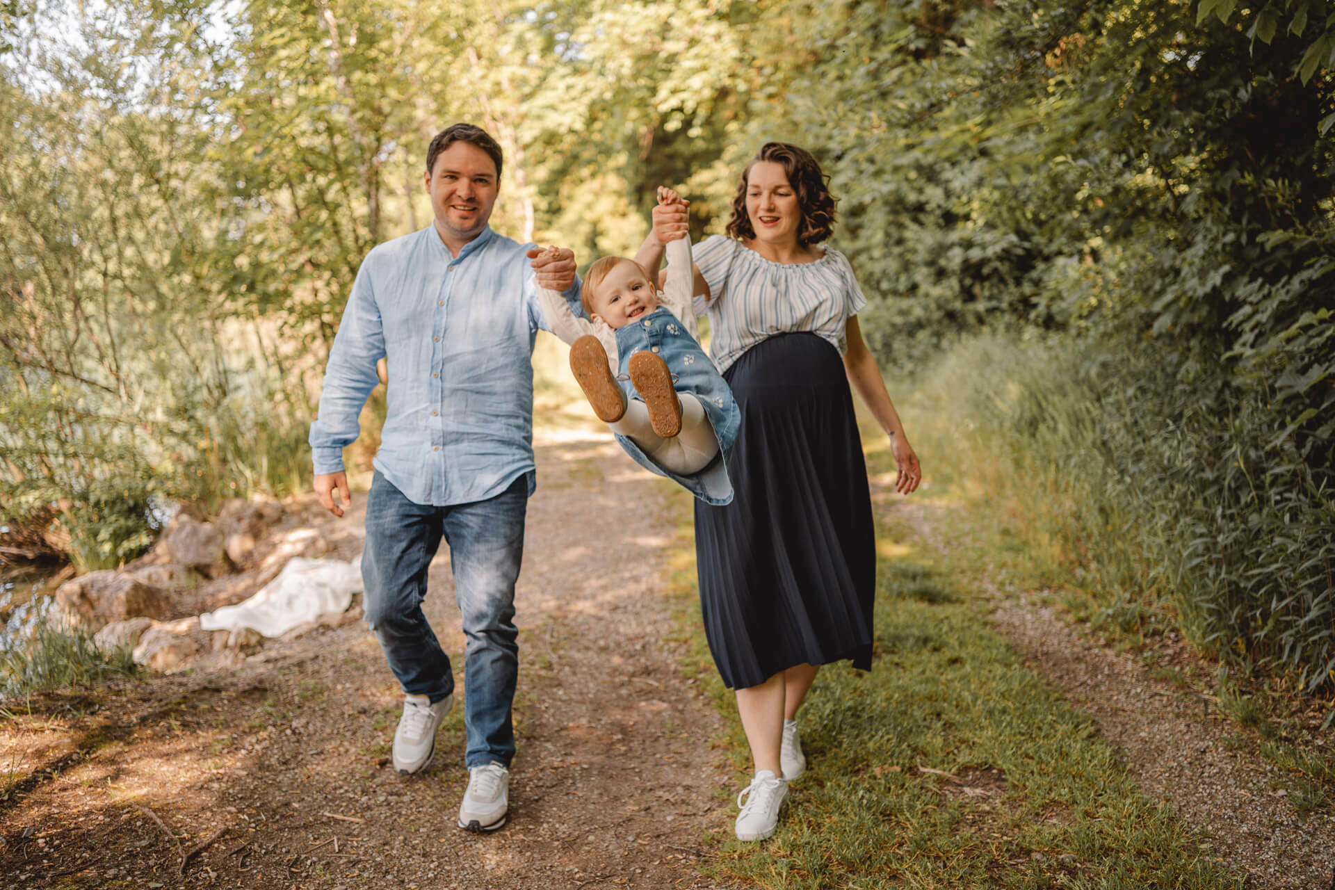 Eltern lassen ihre Tochter an den Händen durch die Luft fliegen bei einem Familien Fotoshooting in München