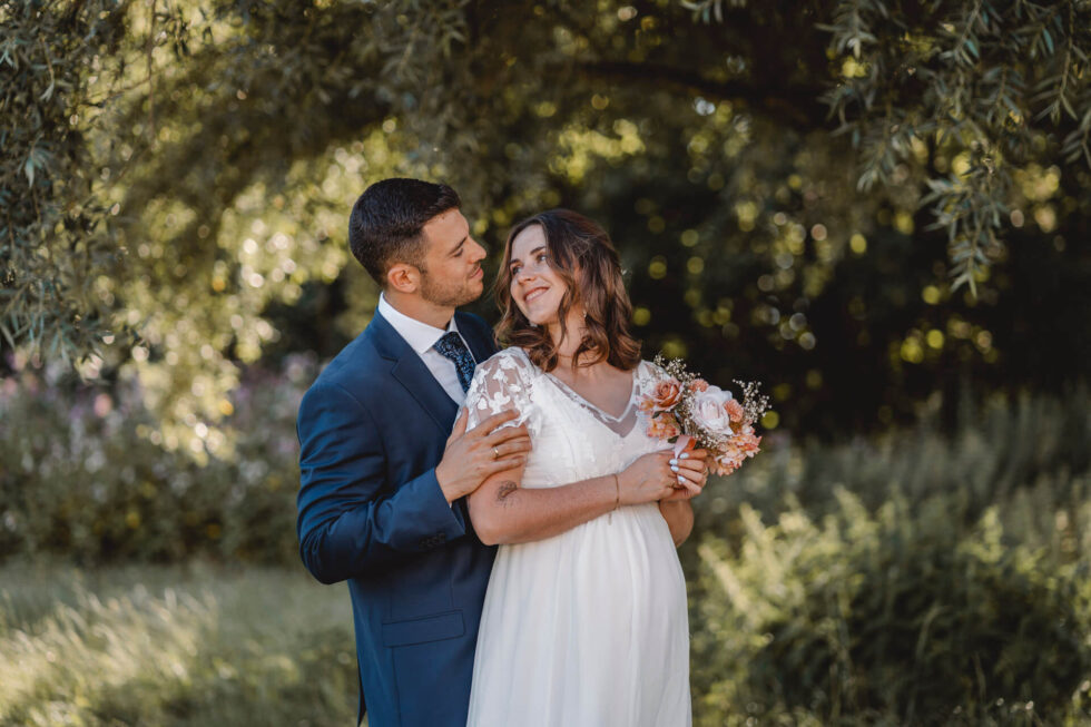 Hochzeitsfoto auf dem ein Bräutigam hinter seiner Braut steht und die beiden sich verliebt anschauen, fotografiert von einer Hochzeitsfotografin in München