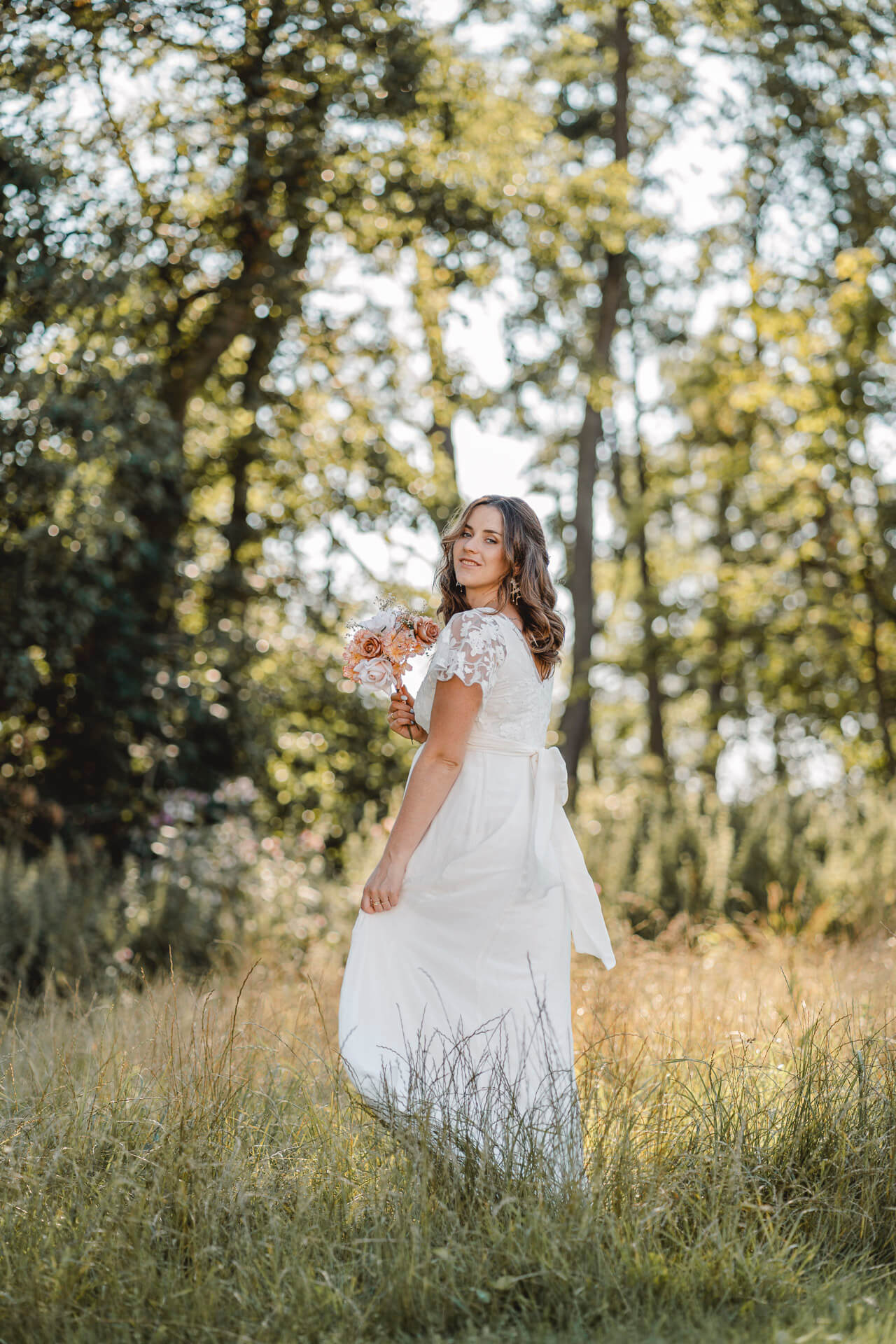 Hochzeitsfoto auf dem eine Braut durch hohes Gras läuft fotografiert von einer Hochzeitsfotografin in München