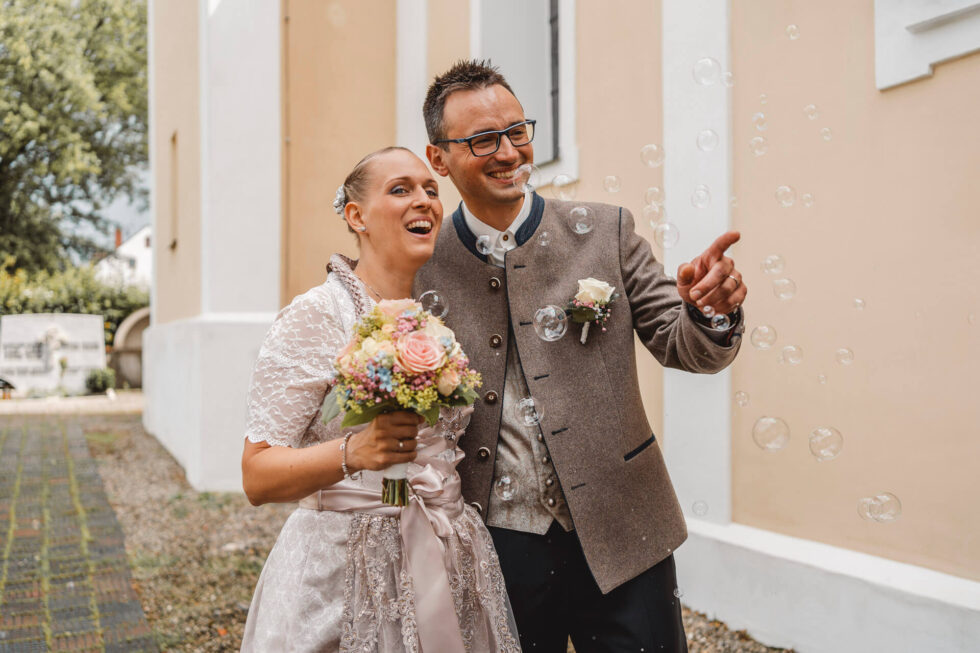Lachendes Brautpaar in Tracht fotografiert von einer Hochzeitsfotografin in München