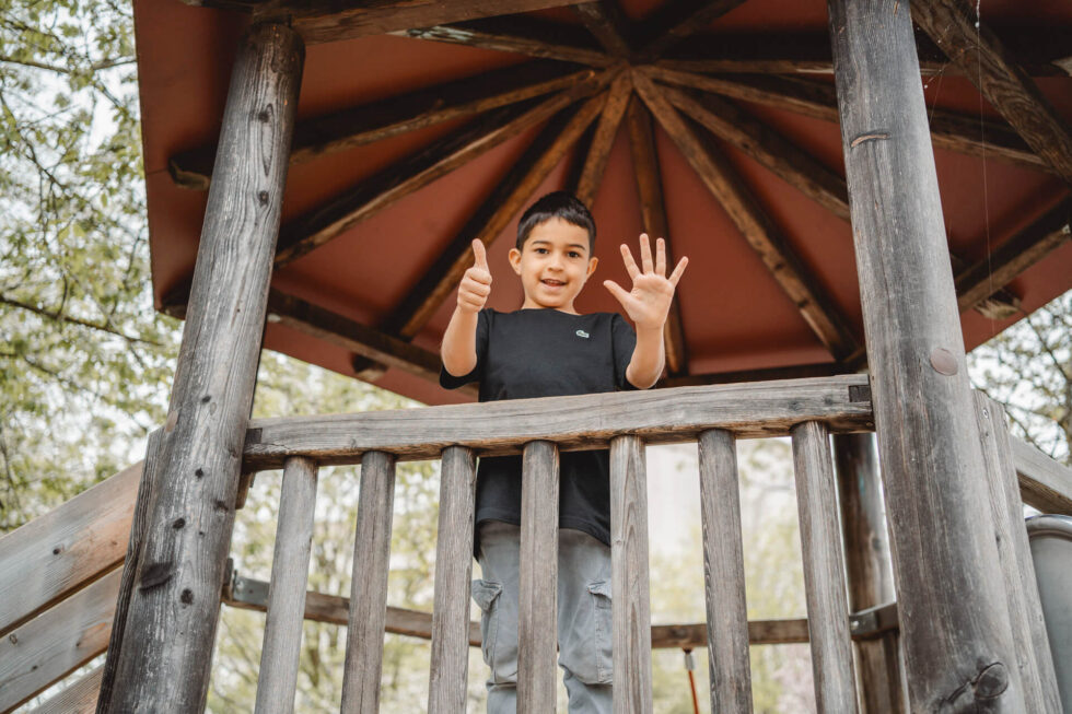 Kindergartenfotografie in München von einem Jungen, der mit seinen Fingern anzeigt, dass er 6 Jahre alt ist