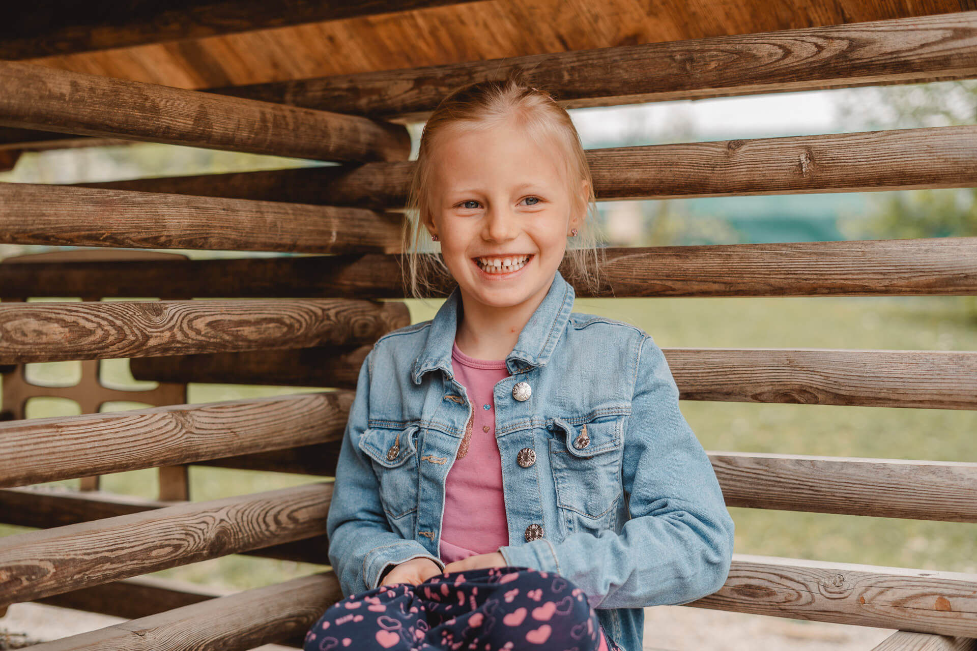 Kindergartenfotografie in München von einem Mädchen, das in einem Spielhaus sitzt